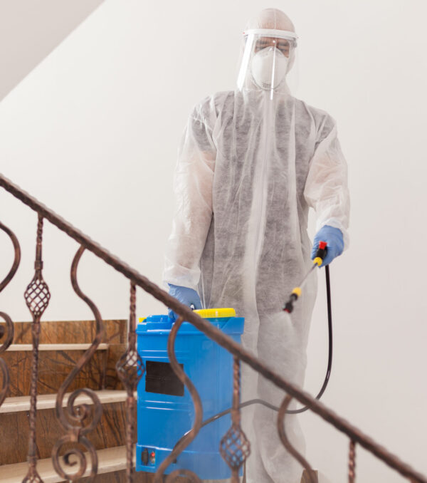 Man spreading disinfectant Man spreading disinfectant against covid-19 wearing biohazard costume.