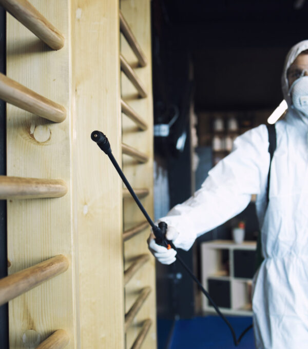 Man in white protection suit disinfecting and fitness equipment and weights to stop spreading highly contagious corona virus. Man in white protection suit disinfecting and fitness equipment and weights to stop spreading highly contagious corona virus.